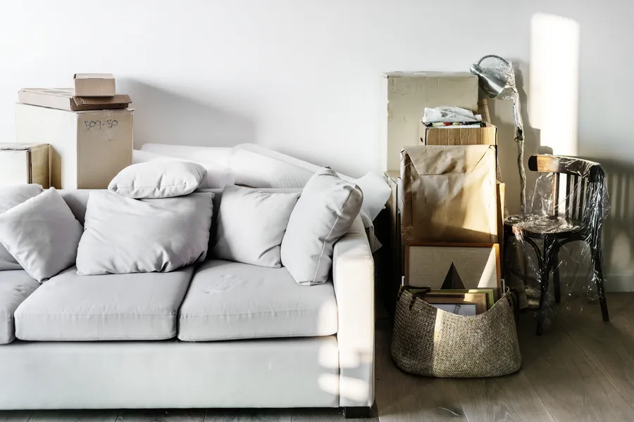 Sofa, packed boxes and a wrapped chair in a living room