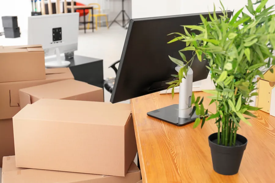 Cardboard boxes beside a desk with a computer monitor in an office